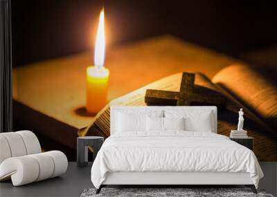 Light candle with holy bible and cross or crucifix on old wooden background in church.Candlelight and open book on vintage wood table christianity study and reading in home.Concept of christ religion Wall mural