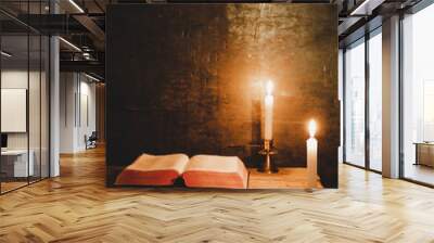 Open Holy Bible and candle on a old oak wooden table. Beautiful gold background. Religion concept. Wall mural