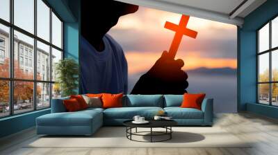 Silhouette of human hand holding the cross, the background is the sunrise., Concept for Christian, Christianity, Catholic religion, divine, heavenly, celestial or god. Wall mural