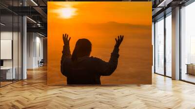 Silhouette of prayer woman worship God in the morning with sunrise sky background. Person hands open palm up worship. God helping repent catholic easter lent mind pray. Christian religion concept. Wall mural