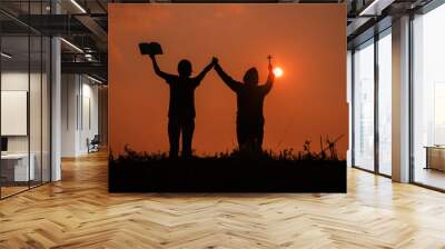 Silhouette of two teen girls praying to god with the bible. Wall mural