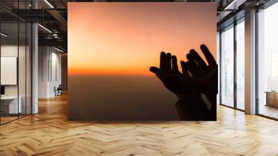 Silhouette of woman hands praying for worship God at sky background. Christians pray to jesus christ for calmness. In morning people got to a quiet place and prayed. Banner with copy space. Wall mural