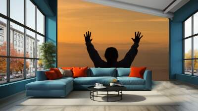 Woman raising his hands in worship. Christian Religion concept. Silhouette woman on sunrise background. Christian female prayers to God in faith. Women raise hands in praise with faith and peace. Wall mural