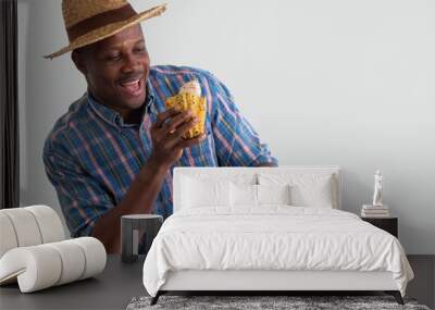 Happy African farmer holding cacao pod and small wooden basket with cacap fruits on white background. Cacao fruits is used as raw ingredient making cocoa or chocolate. Wall mural