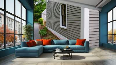 Old tan colored house with white trim and black wood window frame spacers. The glass in the window is wavy and reflects the sun. The exterior wall is made of vintage beige cape cod clapboard siding. Wall mural