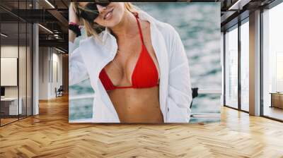 Modelo rubia con bikini rojo y gafas de sol de paseo en una lancha Wall mural