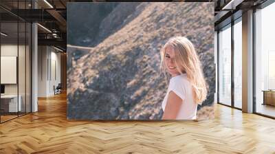 Portrait confident young cheerful smiling blonde woman looks into the camera against the background of bridge and nature on a sunny day. Happy girl smiles broadly Wall mural