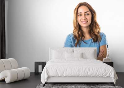 Young woman in a light blue shirt with arms crossed, smiling brightly, isolated on a blank white background. Caucasian girl with long hair and beautiful face Wall mural