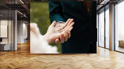 the bride and groom hold wedding rings in their hands Wall mural