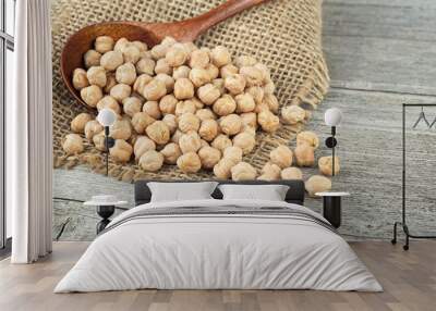 Dried chickpeas in wooden spoon on wooden table. Heap of legume chickpea. Healthy and natural vegetarian food. Wall mural