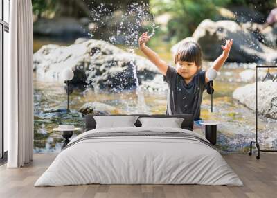 little asian girl playing in waterfall stream with water splash Wall mural