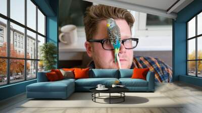 Caucasian Middle Aged Man Sits In His Living Room As Two Colorful Parakeets Perch On His Reading Glasses At Night Wall mural