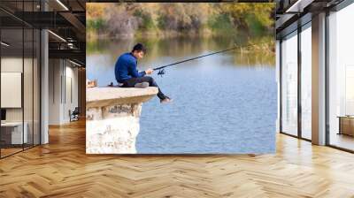 a man is fishing near a river Wall mural