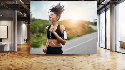 Fitness, sports and happy woman running in a road with music for health, workout or cardio routine. Smile, exercise and African female runner in nature with podcast for training, motivation or energy Wall mural