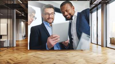 The right team with the right tools for the job. Shot of a team of colleagues using a digital tablet together at work. Wall mural