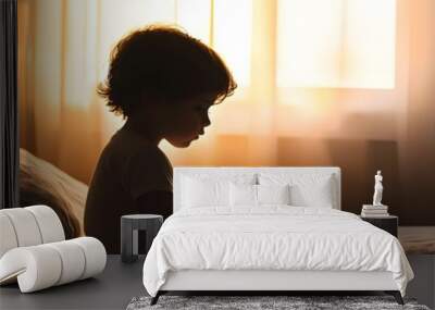 Silhouette of a Small Child Sitting on the Edge of Their Bed Gripping a Pillow Tightly Amid Bedtime Fear and Loneliness Wall mural