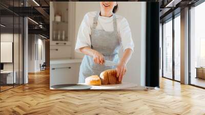 Smiling baker woman slicing bread in a modern kitchen Wall mural