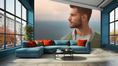 A stylish young man in a side profile, dressed in casual yet chic attire Wall mural