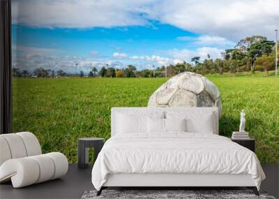 Old leak football/soccer ball abandoned on green grass field. Concept of sadness, hopeless and loneliness. Wall mural