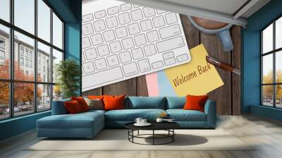 WELCOME BACK WORD ON PAPER NOTE WITH COMPUTER KEYBOARD, HOT COFFEE, AND A PEN ON WOODEN TABLE Wall mural