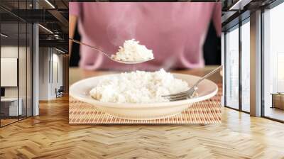 Asian woman eating cooked hot rice by spoon in a white plate  Wall mural