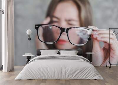 Asian woman holding eyeglasses having headache with eye blur vison Wall mural