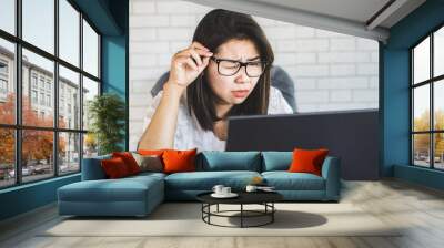 Asian woman worker with eye vision  problem try to watch on computer screen Wall mural