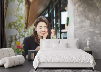 beautiful Asian woman using smart phone and drinking coffee in cafe  Wall mural