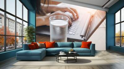 business woman drinking fresh water while working on computer laptop at office desk Wall mural