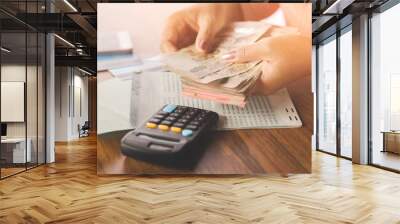 business woman hand counting money paper currency with saving account book and calculator on table  Wall mural