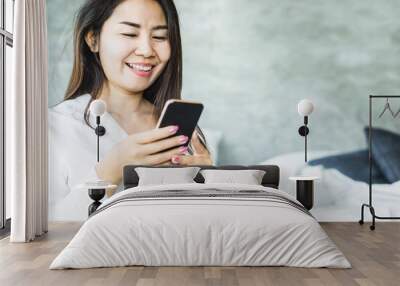 happy Asian woman using smart phone sitting on bed,online shopping,social media concep Wall mural