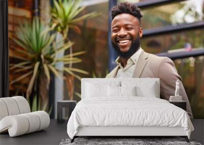 Smiling African American man in a business suit standing in a modern outdoor setting with plants. Wall mural