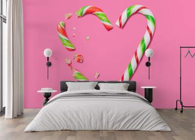 Broken Love minimal concept. Flat lay arrangement heart shape made of two different candy canes against pink background. Wall mural