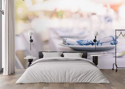 A close-up of a white plate with a blue and white napkin on top set up for an outside party.  Wall mural