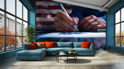 A human hand holds a ballpoint pen and writes on paper. The flag of the United States of America in the background, stars and red and white lines. Wall mural