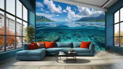 Above and below surface of the Caribbean sea with coral reef underwater and a cloudy blue sky. Wall mural