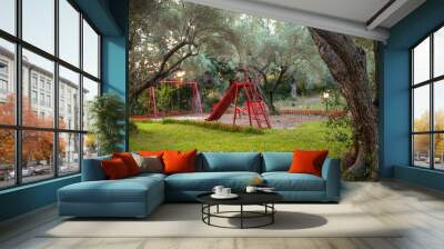 Kids playground under the olive trees in forest. Childrens play area in the park. Safe beautiful red natural playground for children in forest. Wall mural