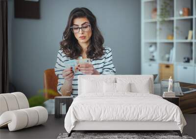 A busy black-haired business woman calculates expenses on a calculator, the number of women estimates household expenses, considers estimating bills and taxes at home Wall mural