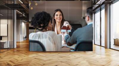 A young man and a woman came to the travel agency. They want to go on a trip during their holidays. Female travel agent giving tickets to young happy couple. Wall mural