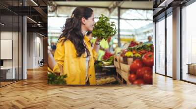 Beautiful woman buying at a farmers market. Smiling girl decided to cook a delicious and healthy meal. Farmer's Market Vegetables. Young woman buying fresh organic produce at a local farmer's market. Wall mural