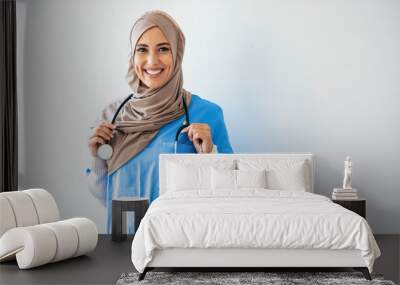 Closeup portrait of friendly, smiling confident muslim female nurse. Authentic Confident Middle Eastern Healthcare Worker. Middle age senior arab nurse woman wearing hijab over isolated background Wall mural