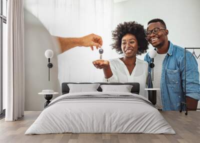 Couple Getting Keys From Realtor Of Their New Home. Portrait of financial adviser congratulating to a young couple for buying a new house. African-American  family buy new house Wall mural