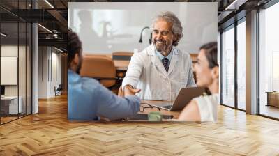 Cropped shot of a handsome mature male doctor and his patient shaking hands in the hospital. Doctor shaking hands with man at hospital. Couple patients visiting health professional.  Wall mural