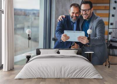 Cropped shot of two businessmen working together on a digital tablet in an office. Two colleagues communicating in corridor, partners walking in the modern office Wall mural