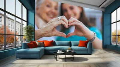 Elderly Woman and Caregiver Forming Heart Shape with Hands Wall mural