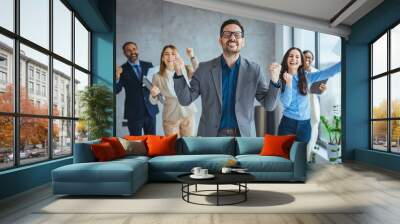 hot of a group of young businesspeople standing together and clapping in a modern office. Shot of colleagues celebrating during a meeting in a modern office.  Wall mural