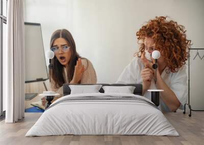 Ill businesswoman blowing and a colleague rejecting her at office.  Businesswoman sneezing in tissue near coworker in office. Young businesswoman suffering from a cold and blowing her nose Wall mural