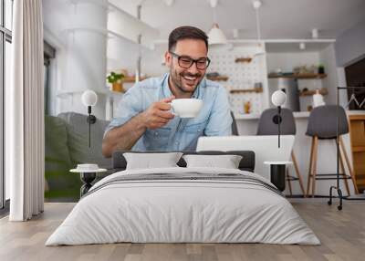 Men working on laptop computer in his room. Home work or study, freelance concept. Young man sitting relaxed on sofa with laptop. Modern businessman using laptop Wall mural