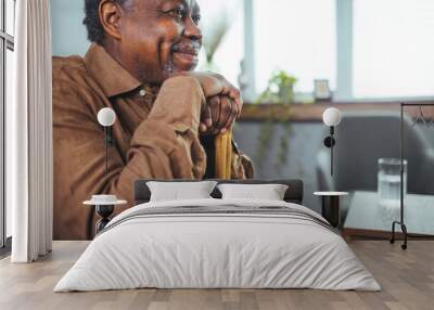 Portrait of a senior man sitting at home with a walking stick. Senior Afro-American with Walking Stick is Sitting in Comfortable Armchair in the Living Room at Home. Wall mural