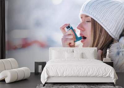 Portrait of a woman using an asthma inhaler in a cold winter with a snowy mountain in the background Wall mural